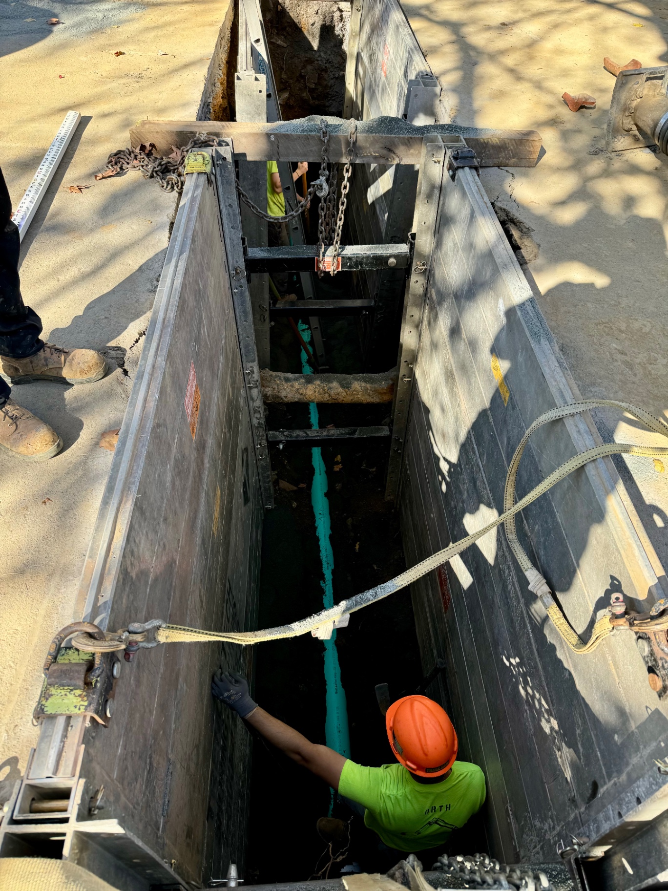 Utility service excavation with trench shoring and pipe installation