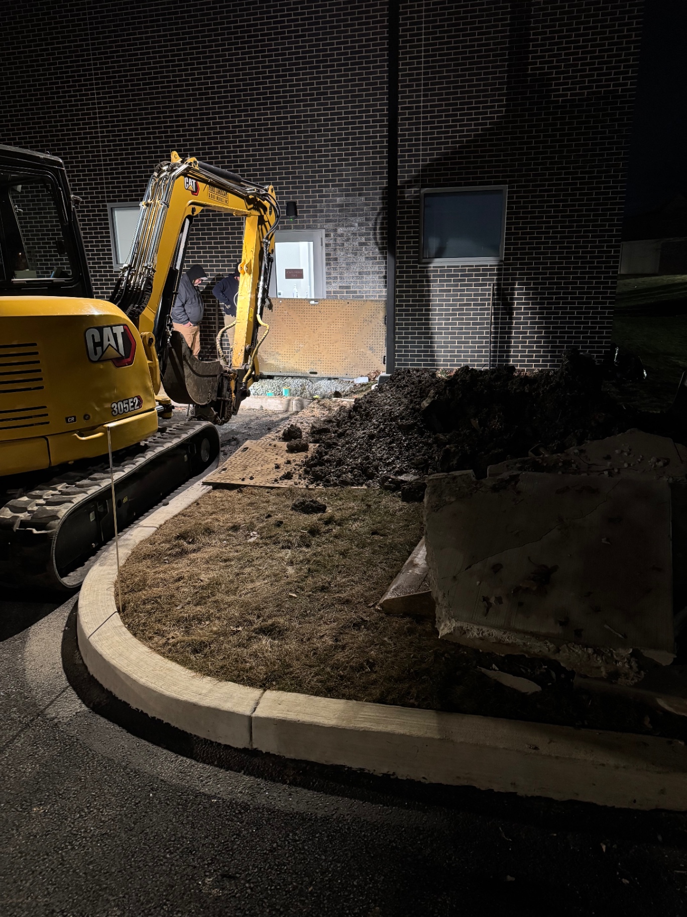 Mini excavator working at night beside a commercial building