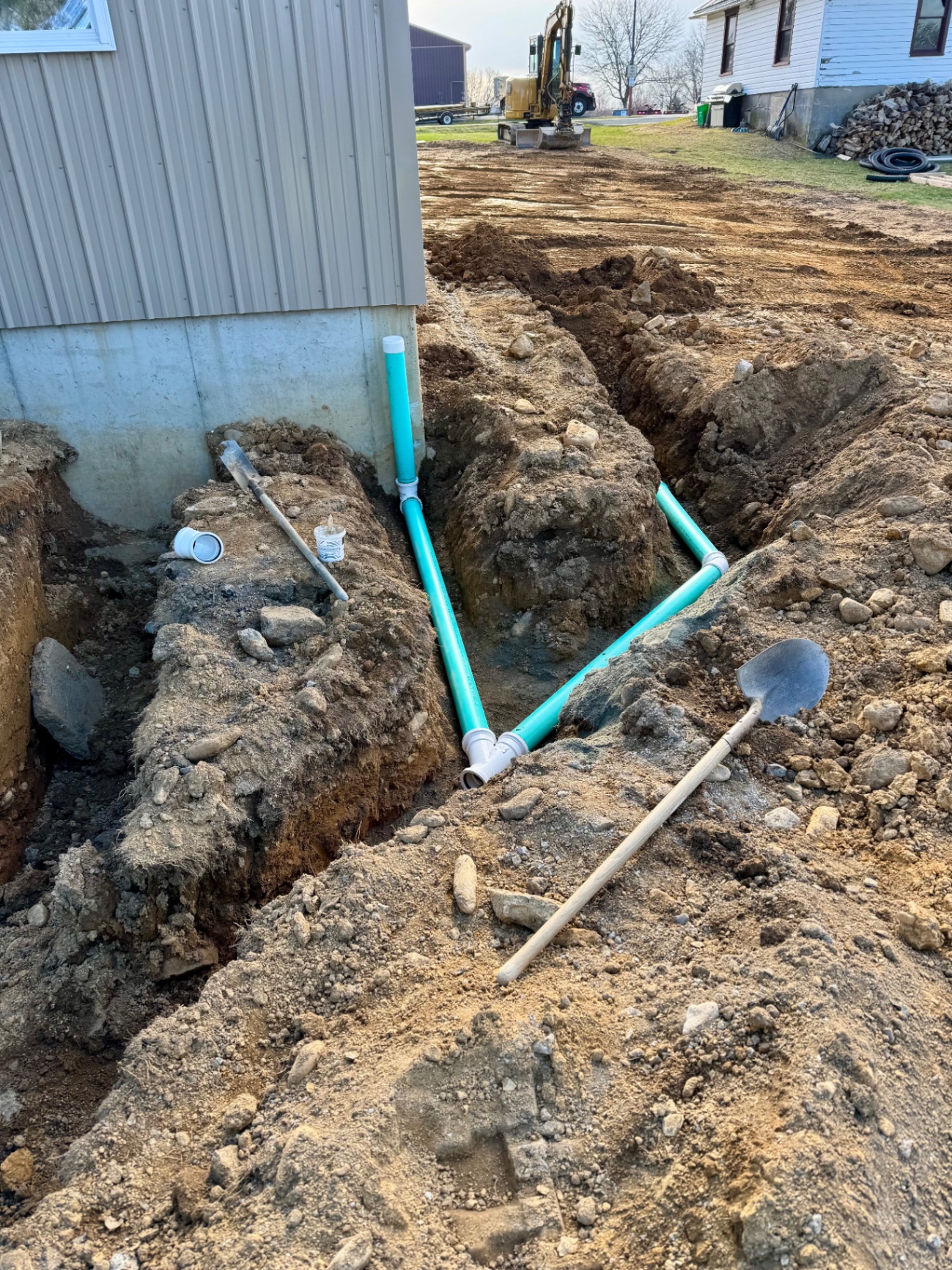 Drainage piping installed in trenches beside a building
