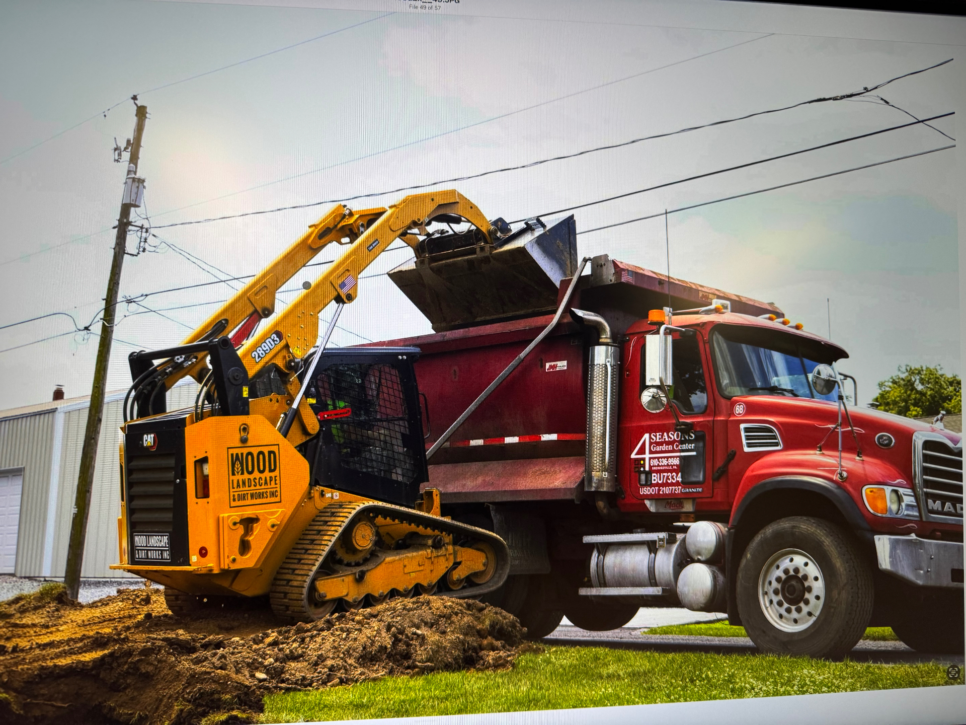 WoodEx skid steer loading a dump truck on a commercial job site