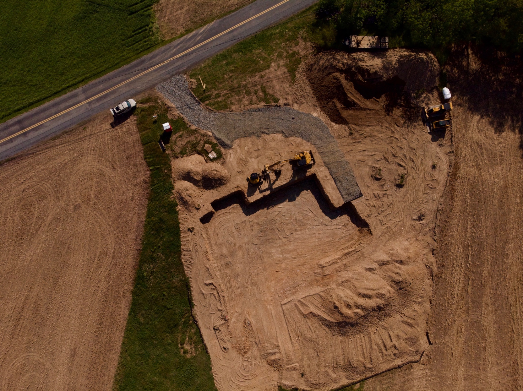 Aerial view of foundation excavation site with excavators and gravel access road